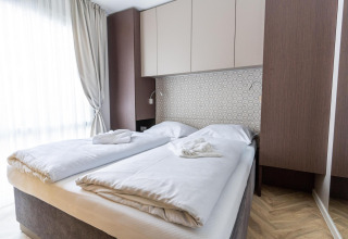 Moderne kamer in Edelweiss lodge met twee bedden, witte lakens en sfeervol, licht interieur met hout.