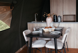 Zona pranzo nella Waterlodge del Recreatiepark De Achterste Hoef, Paesi Bassi, con cucina accogliente.