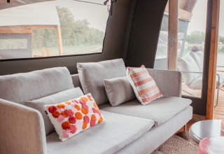 Moderne woonkamer in een Waterlodge op Recreatiepark De Achterste Hoef, met zetel en kleurrijke kussens.