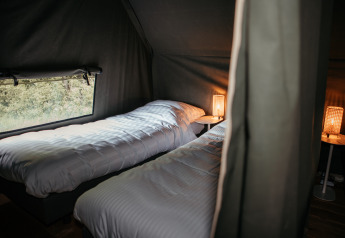 Deux lits simples avec des couettes blanches dans une Waterlodge confortable au Recreatiepark De Achterste Hoef, Pays-Bas.