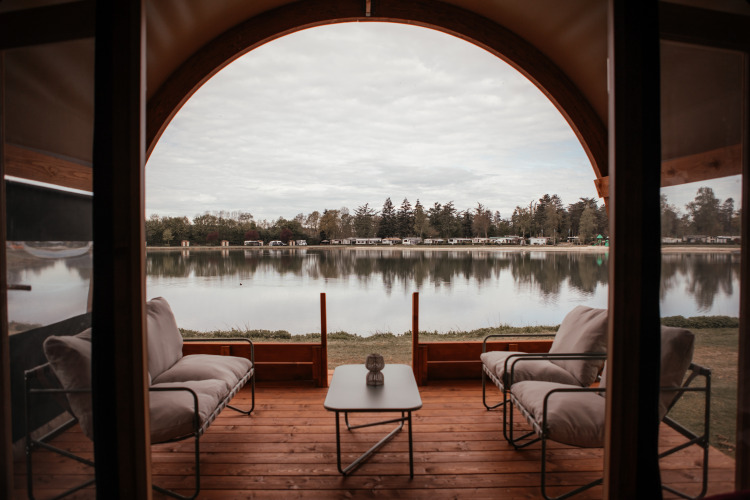 Vista al lago desde la terraza de Waterlodge en Recreatiepark De Achterste Hoef, Países Bajos, con sillones cómodos.