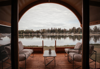 Vista al lago desde la terraza de Waterlodge en Recreatiepark De Achterste Hoef, Países Bajos, con sillones cómodos.