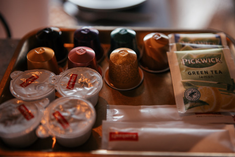 Bakke med Nespresso-kapsler, flødebeholdere, sukkerpakker og Pickwick grøn te ved Waterlodge i Holland.