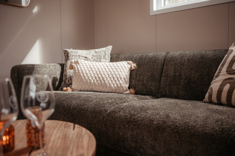 Gemütliche Sofaecke in einem Luxus-Chalet bei Recreatiepark De Achterste Hoef, Niederlande, mit Kissen.