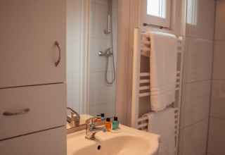 Baño moderno con lavabo y ducha en el Luxury Chalet de Recreatiepark De Achterste Hoef, Países Bajos.