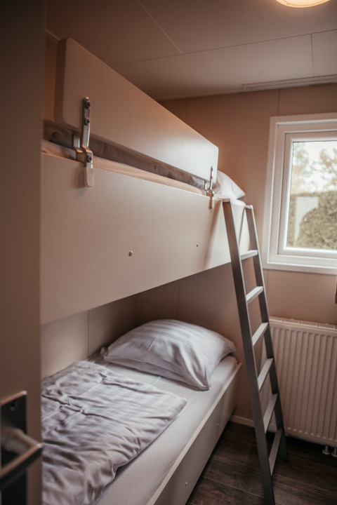 Litera moderna con escalera junto a una ventana en una habitación acogedora en Luxury Chalet, Recreatiepark De Achterste Hoef.