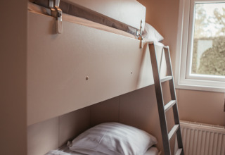 Modern bunk bed with ladder beside a window in a cozy room at Luxury Chalet, Recreatiepark De Achterste Hoef.