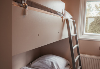 Litera moderna con escalera junto a una ventana en una habitación acogedora en Luxury Chalet, Recreatiepark De Achterste Hoef.