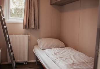 Camera singola accogliente con letto, finestra, scala e armadi in uno chalet di lusso nei Paesi Bassi.