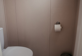 A toilet with toilet paper on the wall and a small bin at Luxury Chalet at Recreatiepark De Achterste Hoef, Netherlands.