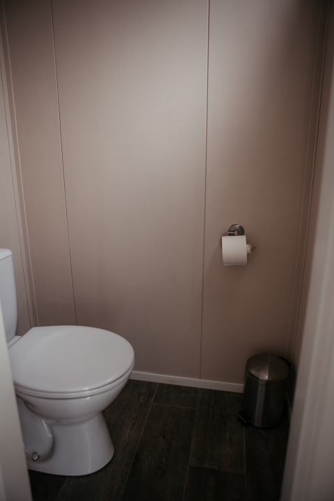 Un bagno con carta igienica sul muro e un piccolo cestino presso il Luxury Chalet a De Achterste Hoef, Paesi Bassi.