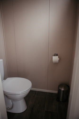 Un inodoro con papel higiénico en la pared y un pequeño cubo en el Luxury Chalet en Recreatiepark De Achterste Hoef, Países Bajos.