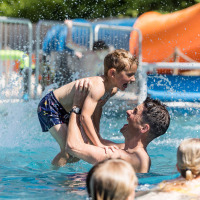 Vader en zoon spelen samen in het zwembad bij Kampeerdorp de Zandstuve, een vakantiepark in Overijssel, Nederland.