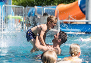 Vater und Sohn spielen im Pool im Kampeerdorp de Zandstuve, einem Ferienpark in Overijssel, Niederlande.