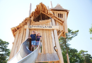 Due bambini giocano su un grande parco giochi di legno con scivolo a Kampeerdorp de Zandstuve, Overijssel.