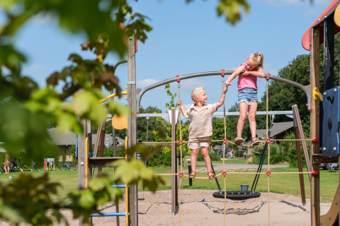 Dos niños juegan en una estructura para trepar en Kampeerdorp de Zandstuve, parque en Overijssel, Países Bajos.