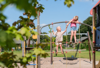 Zwei Kinder spielen auf einem Klettergerüst auf dem Spielplatz im Kampeerdorp de Zandstuve, Overijssel.