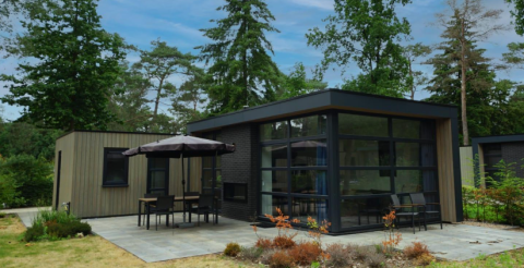 Moderne L-Cube 4+2 lodge bij De Utrechtse Heuvelrug in Nederland, omringd door bos en een ruim terras.