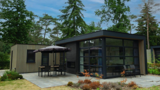 Moderne L-Cube 4+2 lodge op De Utrechtse Heuvelrug, Nederland, met veel glas, terras en groene omgeving.
