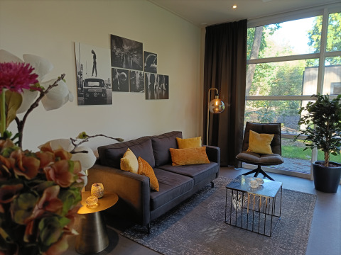 Moderne zithoek in L-Cube 4+2 lodge aan De Utrechtse Heuvelrug, Nederland, met grote ramen en sfeervol design.