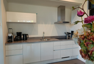 Moderne kitchenette met toestellen en bloemen in de L-Cube 4+2 lodge bij De Utrechtse Heuvelrug, Nederland.