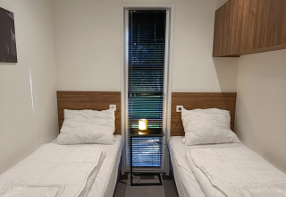 Twee eenpersoonsbedden met witte lakens in een moderne kamer in L-Cube 4+2, De Utrechtse Heuvelrug, Nederland.