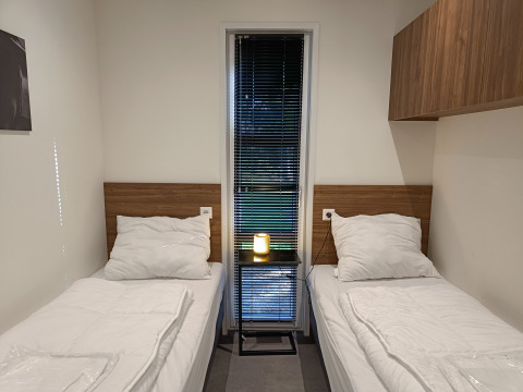 Twee eenpersoonsbedden met witte lakens in een moderne kamer in L-Cube 4+2, De Utrechtse Heuvelrug, Nederland.