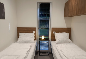 Deux lits simples avec literie blanche dans une chambre moderne au L-Cube 4+2, De Utrechtse Heuvelrug, aux Pays-Bas.