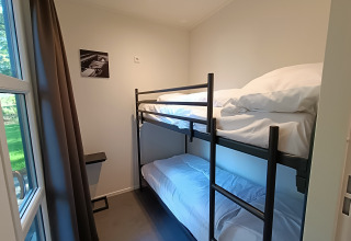 Chambre avec lits superposés, grande fenêtre et décoration minimaliste au L-Cube 4+2 de De Utrechtse Heuvelrug, Pays-Bas.
