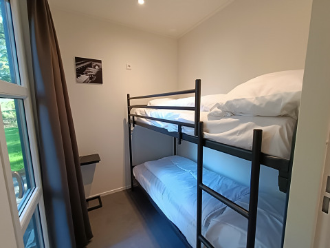 Kamer met stapelbed, groot raam en minimalistisch interieur in L-Cube 4+2 bij De Utrechtse Heuvelrug, Nederland.