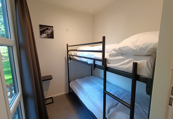 Chambre avec lits superposés, grande fenêtre et décoration minimaliste au L-Cube 4+2 de De Utrechtse Heuvelrug, Pays-Bas.