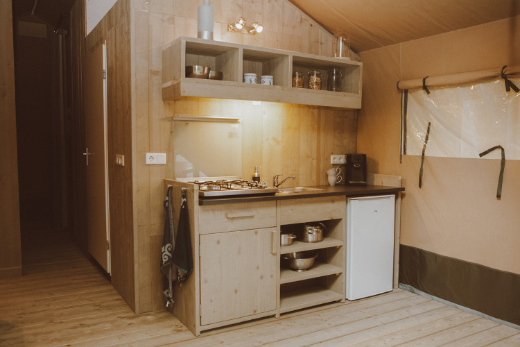 Cocina de tienda safari de lujo con decoración de madera, estufa, fregadero y nevera pequeña en los Países Bajos.