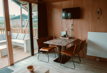 Interior view of Tiny Safari House safari tent at Holiday park De Boshoek, Netherlands, showing dining area and terrace.