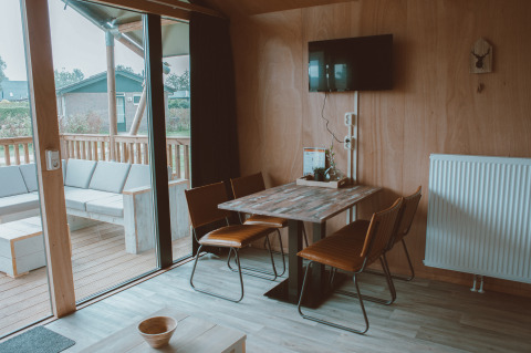 Indvendig udsigt af Tiny Safari House safari-telt på Holiday park De Boshoek, Holland, med spisebord og terrasse.