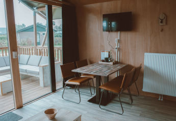 Indvendig udsigt af Tiny Safari House safari-telt på Holiday park De Boshoek, Holland, med spisebord og terrasse.