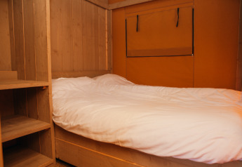 Slaapgedeelte in een safaritent op Vakantiepark De Boshoek, Nederland, met houten planken en bed.