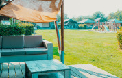 Udsigt fra terrassen ved en safaritelte på Holiday park De Boshoek med legeplads i baggrunden.