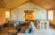 Interior de la carpa Safari Villa en el parque vacacional De Boshoek, Países Bajos, con muebles de madera.