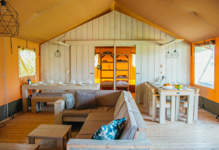 Interior de la carpa Safari Villa en el parque vacacional De Boshoek, Países Bajos, con muebles de madera.