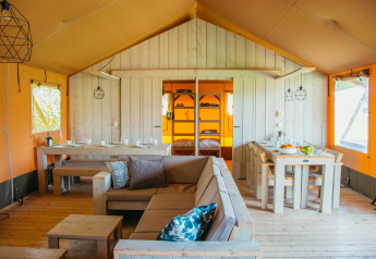 Interior de la carpa Safari Villa en el parque vacacional De Boshoek, Países Bajos, con muebles de madera.