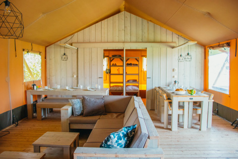 Interior de la carpa Safari Villa en el parque vacacional De Boshoek, Países Bajos, con muebles de madera.