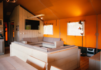 Interior of a safari tent villa with modern seating and TV at Holiday park De Boshoek, Netherlands.