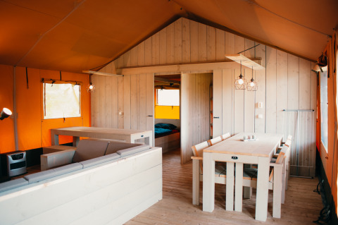 Innenansicht des Safari Villa Safari-Zeltes im Ferienpark De Boshoek, Niederlande, mit Holzmöbeln.