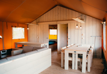 Interieur van de Safari Villa safaritent op Vakantiepark De Boshoek in Nederland met lichte houten meubels.