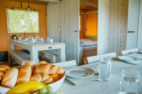 Vista interior de la tienda Safari Villa en De Boshoek, Países Bajos, con mesa preparada para el desayuno.