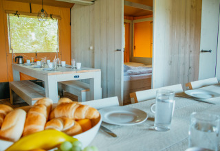 Vista interior de la tienda Safari Villa en De Boshoek, Países Bajos, con mesa preparada para el desayuno.
