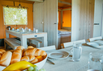Interior view of Safari Villa safari tent at Holiday park De Boshoek in the Netherlands, set for breakfast.