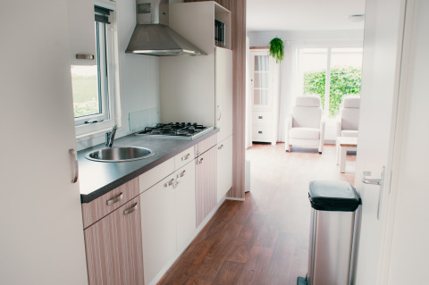 Modern kitchen and bright living area in Veluwelodge at Holiday park De Boshoek, Netherlands, with big windows.