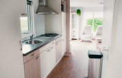 Cucina moderna e soggiorno luminoso nella Veluwelodge al Holiday park De Boshoek, Paesi Bassi, con ampie finestre.