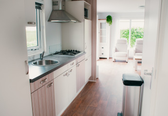 Modern kitchen and bright living area in Veluwelodge at Holiday park De Boshoek, Netherlands, with big windows.